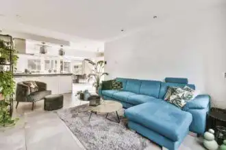 Bright contemporary living room with stylish blue sectional sofa and lush greenery.