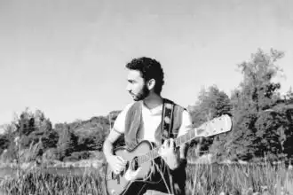 Guitarist playing guitar outdoors in a scenic natural setting, ideal for music lovers and nature enthusiasts.