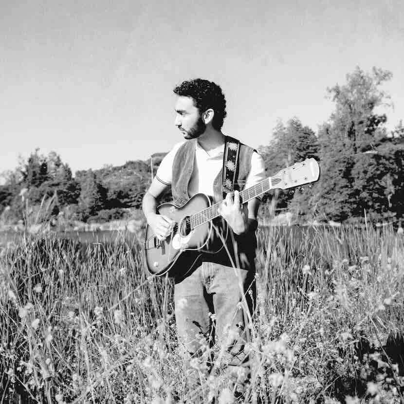 Guitarist playing guitar outdoors in a scenic natural setting, ideal for music lovers and nature enthusiasts.