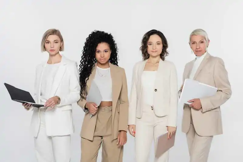Diverse professional women in business suits holding laptops and documents for leadership and empowerment.