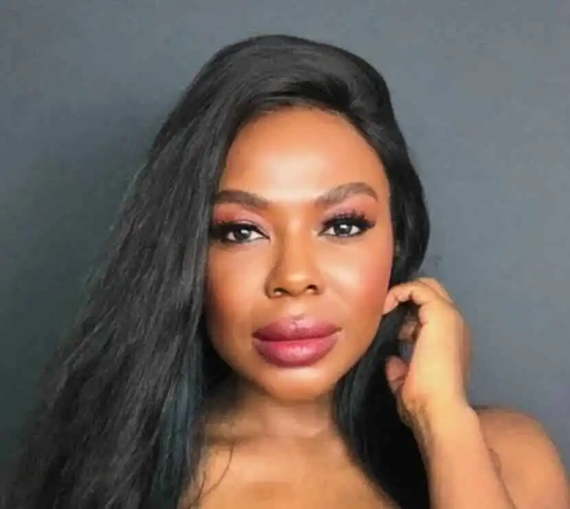 Close-up of confident Black woman with flawless skin and long black hair, indoors.