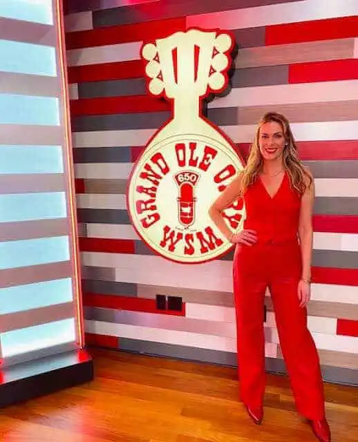 Bright woman in red jumpsuit at Grand Ole Opry stage.