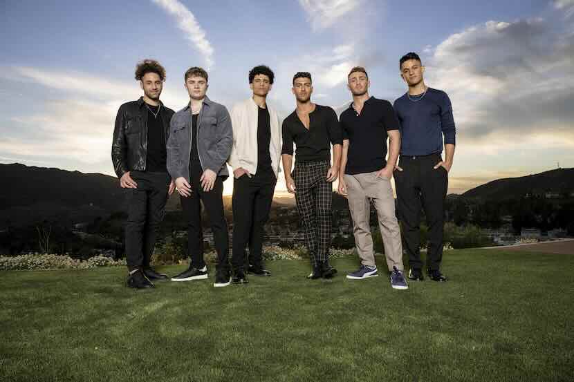 LGBTQ+ men standing outdoors at sunset.