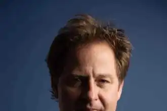 Close-up of handsome man with confident expression, dark background.