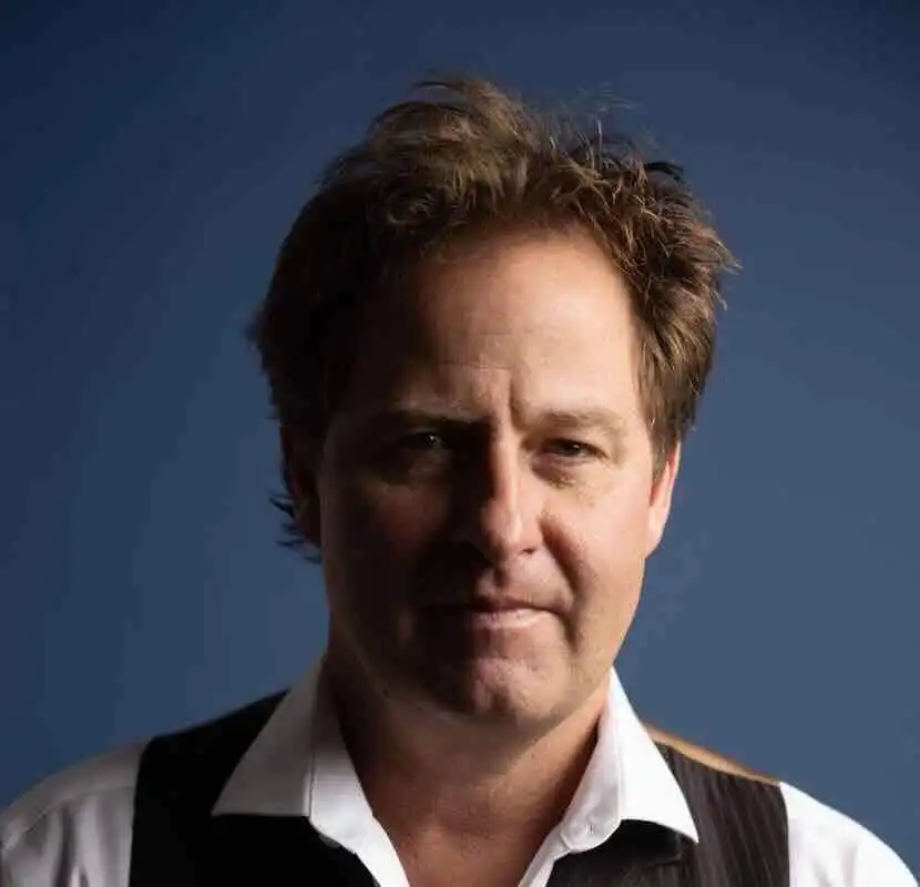 Close-up of handsome man with confident expression, dark background.