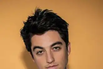 Close-up of young man with styled dark hair and clear skin, posing against a warm background, representing modern masculinity and confidence.