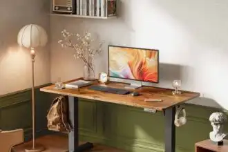Stylish desk with computer, lamp, and decorative items in a cozy workspace.