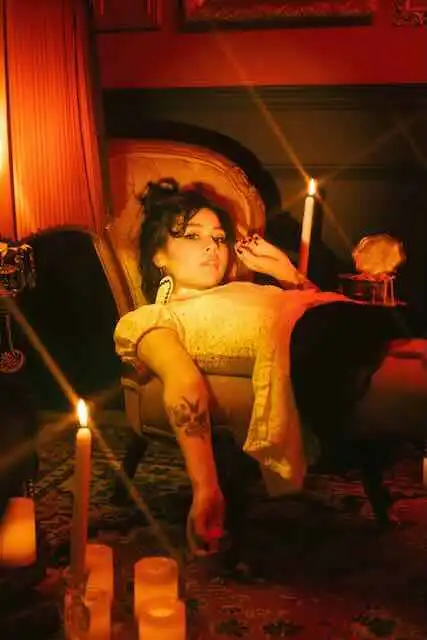 A woman relaxing on a vintage sofa with candles creating an intimate, cozy atmosphere.