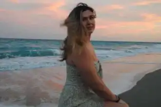 A woman enjoying a peaceful moment by the ocean during sunset, highlighting tranquility and natural beauty.