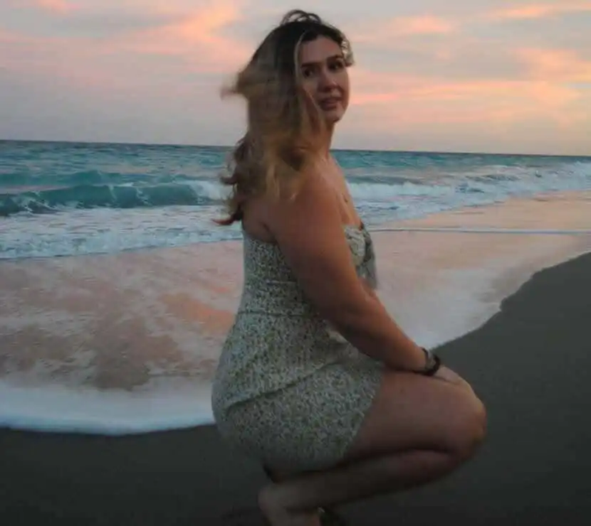 A woman enjoying a peaceful moment by the ocean during sunset, highlighting tranquility and natural beauty.