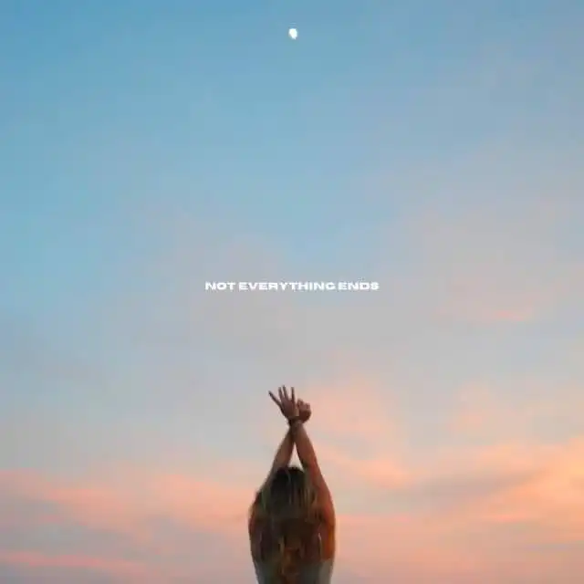 Person reaching towards sky during sunset.