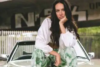 Portrait of a confident woman sitting on a car outdoors, casual fashion, natural setting.
