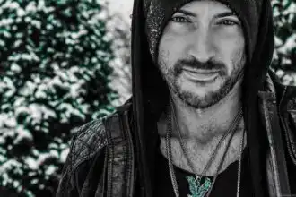 LGBTQ+ male model in winter outdoor snowy scene, stylish black leather jacket and jewelry for pride photos.