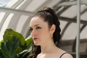 Portrait of a woman in a greenhouse with vibrant green plants, showcasing lifestyle and nature inspiration.