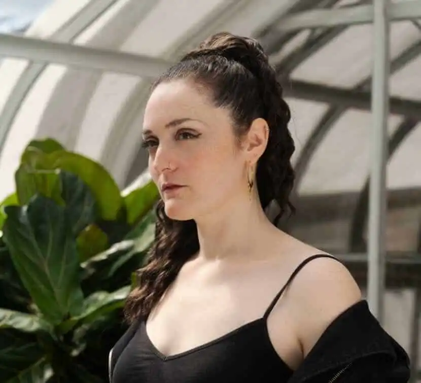 Portrait of a woman in a greenhouse with vibrant green plants, showcasing lifestyle and nature inspiration.