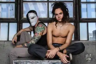 Vulnerable models: man with tattooed arm and masked face, shirtless woman sitting on ledge.
