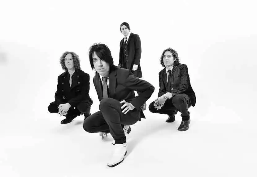 Vegan magazine photo of diverse band members in stylish black suits, posing confidently for a modern, edgy look.