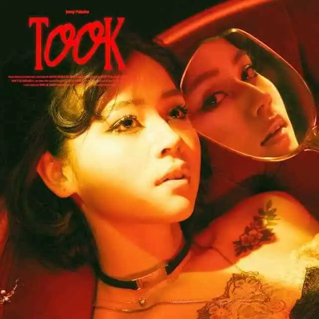 Elegant woman with bold makeup and tattoos, looking thoughtfully into the mirror.