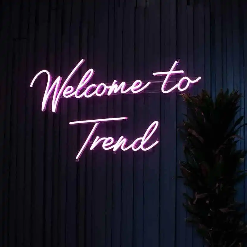 Neon sign reading "Welcome to Trend" against dark wall, stylish decor for modern venues.