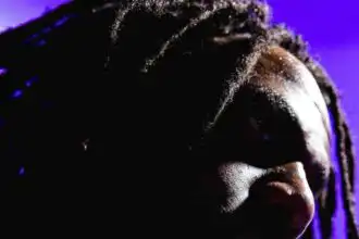 Close-up of an African American man with dreadlocks and intense lighting, showcasing diversity.