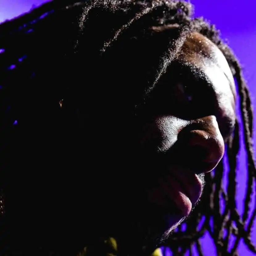 Close-up of an African American man with dreadlocks and intense lighting, showcasing diversity.