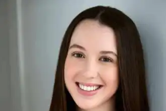 Young smiling woman with long brown hair in casual red top, showcasing confidence and beauty.