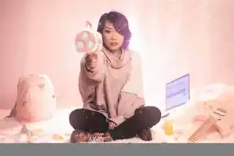 A confident woman sitting on the floor, holding a toy gun, with a laptop and backpack in a cozy, playful setting.