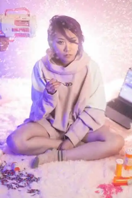 Young woman in cozy hoodie enjoying candy, surrounded by colorful toys and snowflakes.