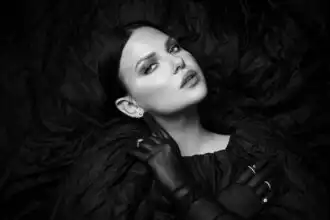 Glamorous black and white photo of a woman with intense gaze, stylish attire, and jewelry.