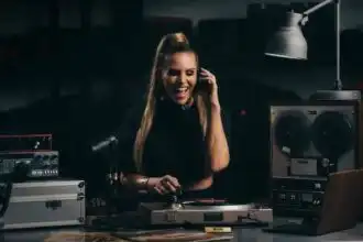 Happy female DJ playing music with headphones, professional DJ equipment in a recording studio.