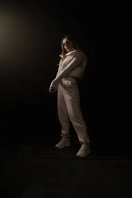 Ally wearing stylish beige outfit in dramatic lighting for Divine Magazine feature.