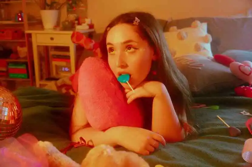 A young woman with long dark hair lies on a bed, surrounded by colorful toys and candies, romantic and playful atmosphere.