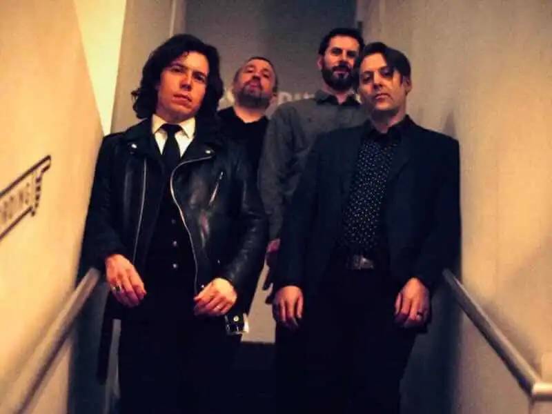 A group of four men with dark, edgy fashion style standing on a staircase, representing diverse personalities at Divine Magazine event.