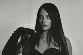 Elegant woman with long dark hair singing into vintage microphone, stylish black dress.