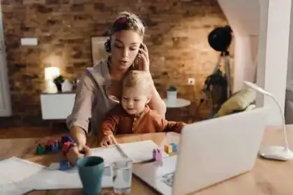 Mother helping her young child with educational toys and a laptop in a cozy home setting.