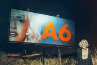 Large A6 billboard displaying a close-up of a woman's face with bold makeup and jewelry.