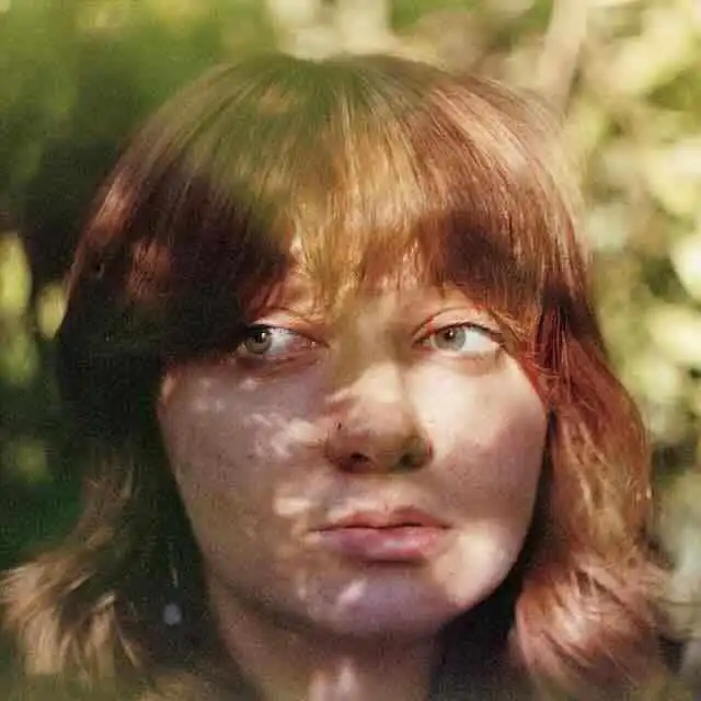 Close-up of a young woman with red hair in natural sunlight.