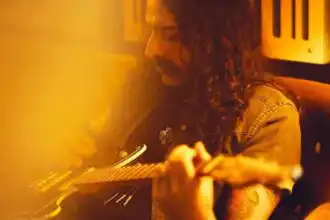 Close-up of a woman playing acoustic guitar in warm, inviting studio setting.