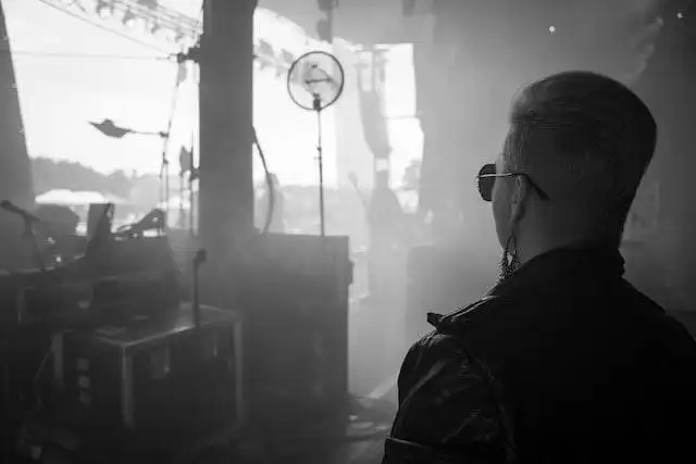 Mysterious man wearing sunglasses in a dimly lit, smoky environment, adding an intriguing vibe.