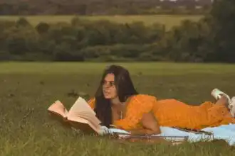 Woman lying on grass reading a book outdoors, enjoying nature and peaceful moments.