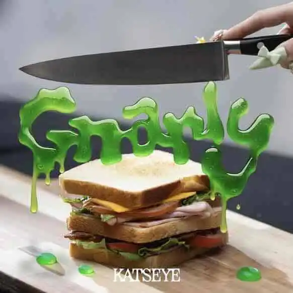 A close-up of a sandwich with green "greedy" syrup melting onto it, with a knife poised above.