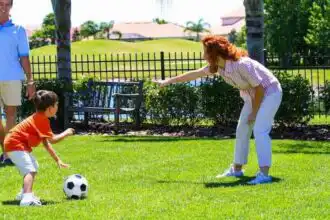 Family playing soccer in a park with kids and parents enjoying outdoor activities.