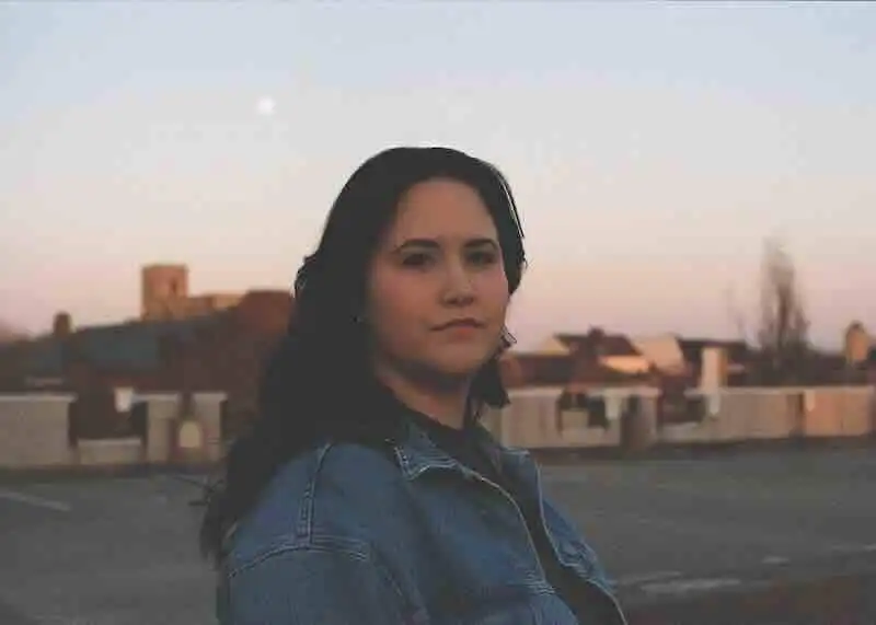Confident woman standing outdoors at sunset, representing strength and resilience.