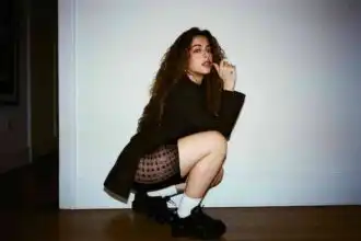 Fashion model crouching in stylish outfit, highlighting urban fashion trends and confident attitude.