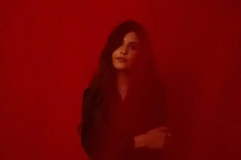 Elegant woman with dark hair against red background, embracing LGBTQ+ pride and self-expression.