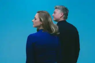 Two adults standing close together against a blue background, showcasing connection and intimacy.