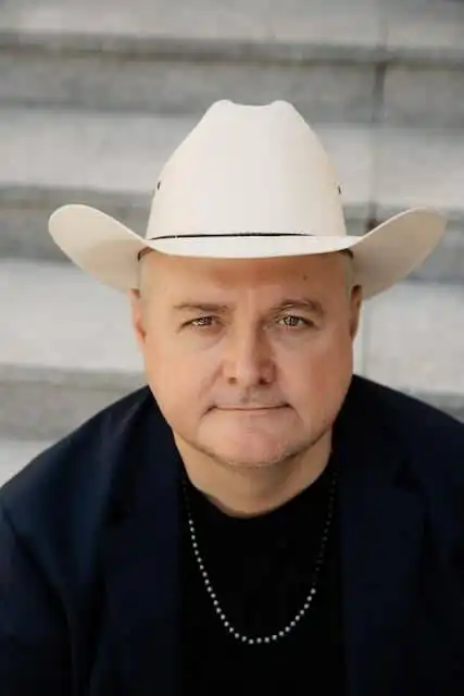 Close-up of a man wearing a cowboy hat, highlighting LGBTQ+ friendly content on Divine Magazine.