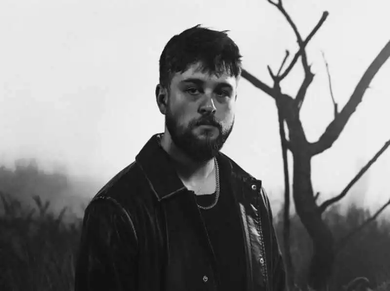 Portrait of a man with a leather jacket in a moody outdoor setting.