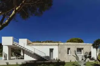 Beautiful white villa with outdoor staircase and lush greenery, perfect for relaxation and luxury escapes.