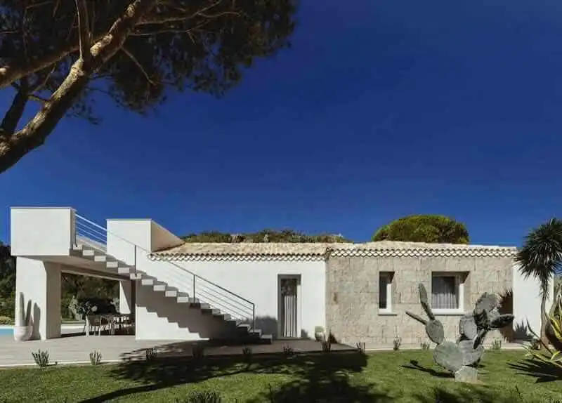 Beautiful white villa with outdoor staircase and lush greenery, perfect for relaxation and luxury escapes.